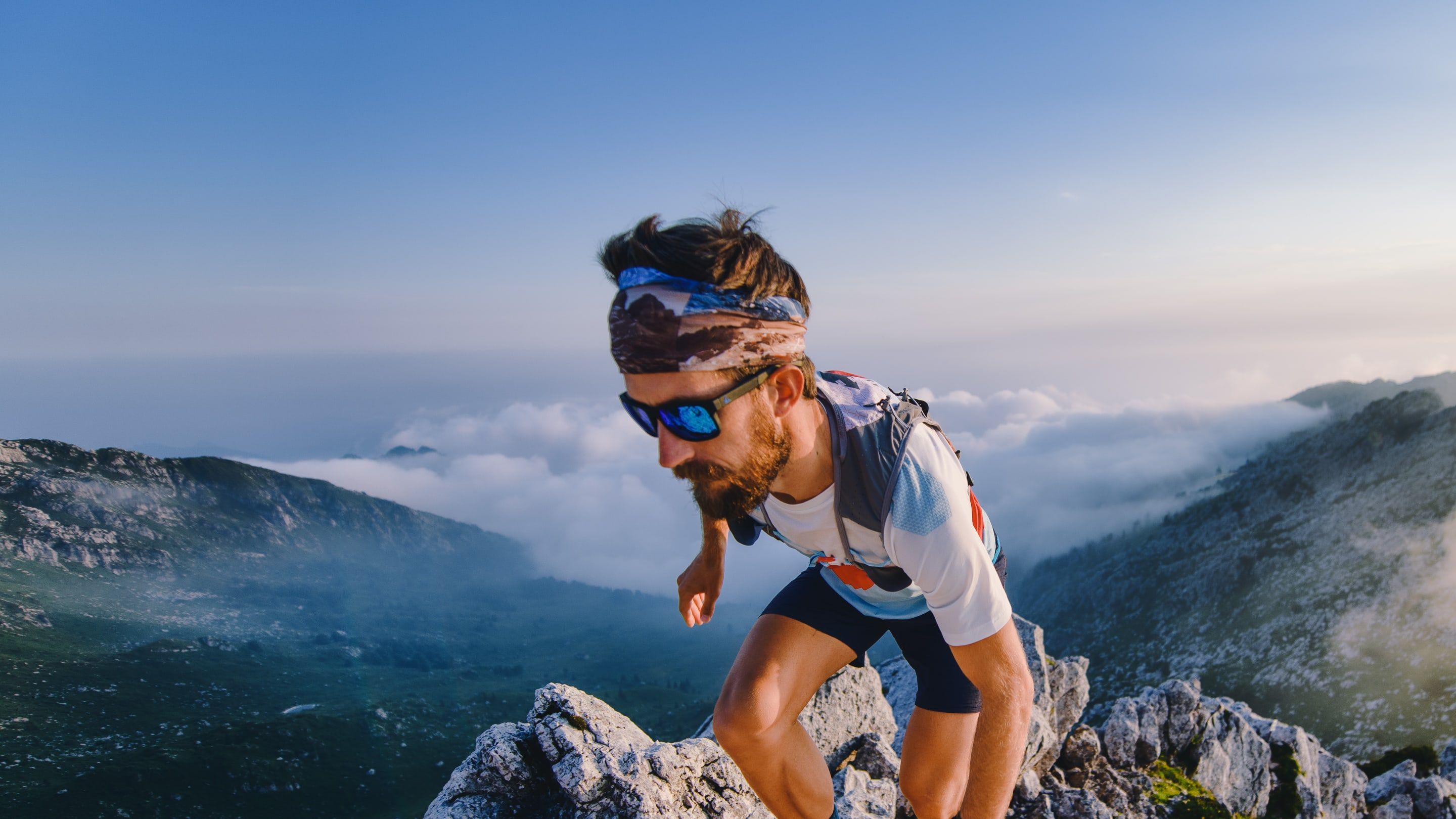 A trail runner climbing a rocky ridge high above the clouds.